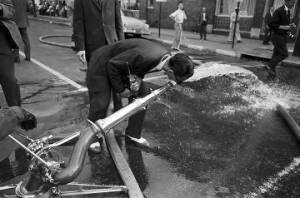 Man drinking water from a fire hose during the Children's Crusade in Birmingham, Alabama.