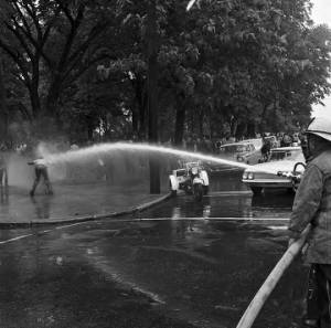 Firemen spraying a civil rights demonstrator with a hose at Kelly Ingram Park during the Children's Crusade in downtown Birmingham, Alabama.