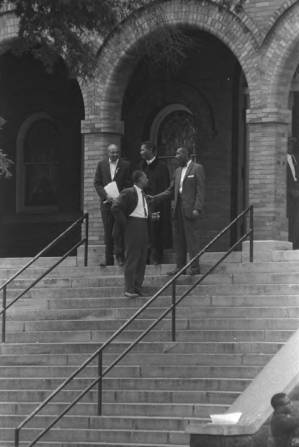 Four African American men on the front steps of 16th Street Baptist Church in Birmingham, Alabama, after the building was bombed.