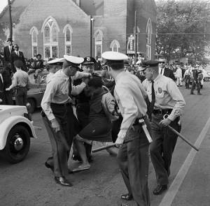 Police officers arresting an African American woman during a civil rights demonstration on 6th Avenue North in Birmingham, Alabama.