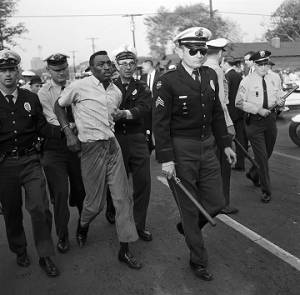 Police officers arresting an African American man during a civil rights demonstration on 6th Avenue North in Birmingham, Alabama.