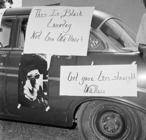 Posters on vehicles during a demonstration held to protest Governor George Wallace's visit to Hobson City, Alabama.