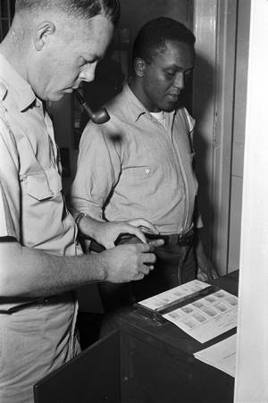 Member of the Dallas County sheriff's department fingerprinting a young African American man who was arrested during a civil rights demonstration in Selma, Alabama.