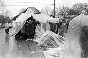 Civil rights demonstrators standing under tarps in the rain during the "Berlin Wall" demonstrations on Sylvan Street in Selma, Alabama.