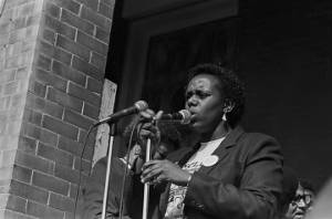 Woman speaking from the steps of Brown Chapel AME Church in Selma, Alabama, during the 20th anniversary commemoration of the Selma to Montgomery March.