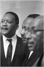 Martin Luther King, Jr., standing with L. L. Anderson and another man during a meeting at Tabernacle Baptist Church in Selma, Alabama.