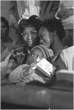 Women and young child in a church building in Greenville, Alabama, probably listening to Martin Luther King, Jr., speak.