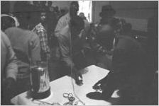 Group of people in line in front of a table in a small wooden church building in Lowndes County, Alabama.