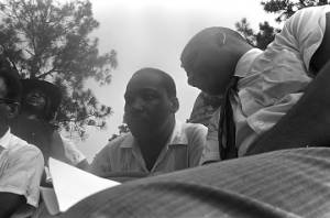 Whitney M. Young, Jr., speaking to Martin Luther King, Jr., while seated on a platform in front of the state capitol in Jackson, Mississippi, at the end of the "March Against Fear" begun by James Meredith.