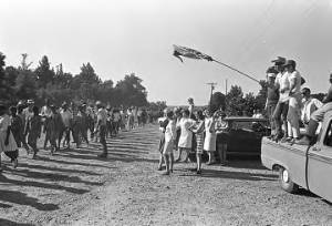 Groups of white people on the side of a dirt road, observing the "March Against Fear" begun by James Meredith.