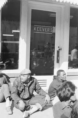 Students from Tuskegee Institute seated on the sidewalk outside Keever's, during a demonstration to protest the murder of Samuel L. Younge, a civil rights worker.