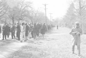 Students from Tuskegee Institute marching down a sidewalk during a demonstration to protest the murder of Samuel L. Younge, a civil rights worker.