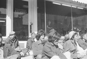 Students from Tuskegee University seated on the sidewalk in front of Keever's store during a demonstration to protest the murder of Samuel L. Younge, a civil rights worker.
