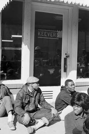 Students from Tuskegee Institute seated on the sidewalk outside Keever's, during a demonstration to protest the murder of Samuel L. Younge, a civil rights worker.