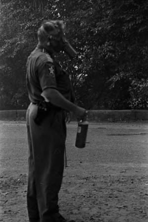 Police officer wearing a gas mask and carrying a can of tear gas during a civil rights demonstration in Greensboro, Alabama.