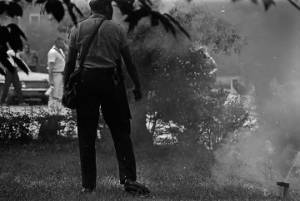 Police officer standing beside a cloud of tear gas during a civil rights demonstration in Greensboro, Alabama.