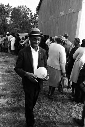 John Hulett walking past people standing in line to vote in Lowndes County, Alabama.