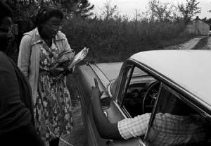 Two women talking to a man in the driver's seat of a car, while canvassing voters for the Lowndes County Freedom Organization.