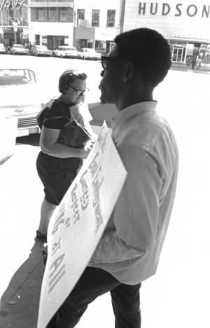 Young man carrying a sign on the sidewalk outside the S. H. Kress & Co. department store on Dexter Avenue in downtown Montgomery, Alabama.