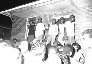 Man addressing an audience in front of an apartment building at Cleveland Court in Montgomery, Alabama, during a civil rights rally.