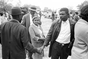Men shaking hands while standing in line outside on election day in Lowndes County, Alabama.