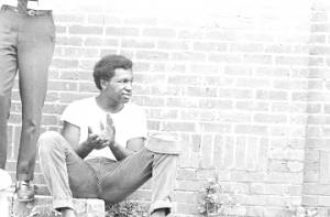Young man seated against a wall of the First Missionary Baptist Church in Prattville, Alabama, during a meeting of the Autauga County Improvement Association.