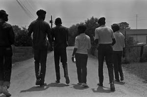 Young men and women walking down a dirt road in a neighborhood in Montgomery, Alabama, while canvassing voters in the city.