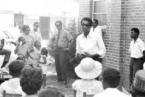 Stokely Carmichael speaking to a group of people standing outside the First Missionary Baptist Church in Prattville, Alabama, during a meeting of the Autauga County Improvement Association.