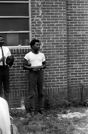 Men standing against the First Missionary Baptist Church in Prattville, Alabama, during a meeting of the Autauga County Improvement Association.