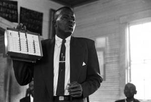 Willie Lee Wood, Sr., demonstrating a voting machine for an audience in a small wooden church building in Prattville, Alabama.