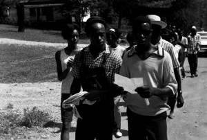 Edward Rudolph and another man, reading a sheet of paper while leading marchers down a street in Prattville, Alabama, during a demonstration sponsored by the Autauga County Improvement Association.