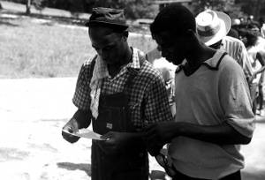 Edward Rudolph and another man, reading a sheet of paper while leading marchers down a street in Prattville, Alabama, during a demonstration sponsored by the Autauga County Improvement Association.
