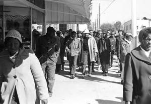 Simuel Schutz, Jr., Wendell Paris, and other students from Tuskegee Institute marching down a sidewalk during a demonstration to protest the murder of Samuel L. Younge, a civil rights worker.
