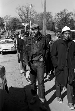 Wendell Paris and other students from Tuskegee Institute marching down a sidewalk on Old Montgomery Road during a demonstration to protest the murder of Samuel L. Younge, a civil rights worker.