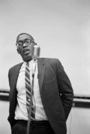 Dr. Burcham Phillips speaking during a meeting in the Tuskegee Institute gymnasium, which was held to discuss student demonstrations protesting the murder of Samuel L. Younge.