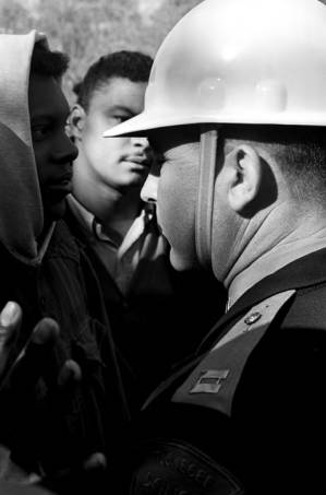 Simuel Schutz, Jr., speaking to policemen who have lined up across a road to block their demonstration in Tuskegee, Alabama, to protest the murder of Samuel L. Younge, a civil rights worker.