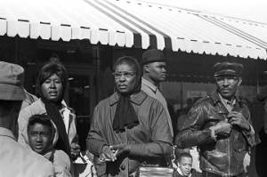 Women and men standing in front of a store in downtown Tuskegee, Alabama, during a student demonstration to protest the murder of Samuel L. Younge, a civil rights worker.