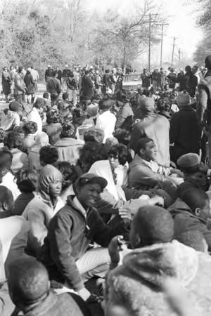 Students from Tuskegee Institute seated on a road during a demonstration to protest the murder of Samuel L. Younge, a civil rights worker.