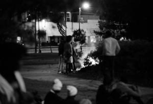 People standing around a fire in the town square near the Confederate monument in Tuskegee, Alabama, during a student demonstration to protest the murder of Samuel L. Younge, a civil rights worker.
