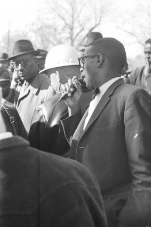 Dr. Burcham Phillips speaking into a microphone during a student demonstration in Tuskegee, Alabama, to protest the murder of Samuel L. Younge, a civil rights worker.