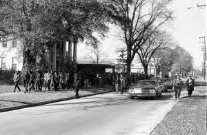 Students from Tuskegee Institute marching down a sidewalk downtown during a demonstration to protest the murder of Samuel L. Younge, a civil rights worker.