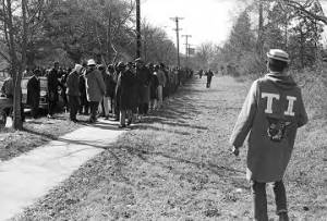 Students from Tuskegee Institute marching down a sidewalk during a demonstration to protest the murder of Samuel L. Younge, a civil rights worker.