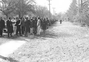 Students from Tuskegee Institute marching down a sidewalk during a demonstration to protest the murder of Samuel L. Younge, a civil rights worker.