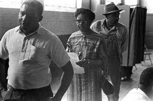 Woman and two men standing in line during a voter registration drive at the Fort Charles Henderson armory in Troy, Alabama.