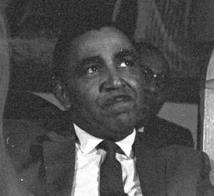 Joseph Lowery sitting behind the podium, listening to Martin Luther King, Jr., speak during a meeting at St. Paul AME Church in Birmingham, Alabama.