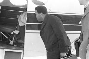 Hosea Williams holding a briefcase and looking inside the door of a plane at the airport in Montgomery, Alabama.