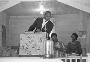 Ralph Featherstone speaking to an audience in a small wooden church building in Lowndes County, Alabama.