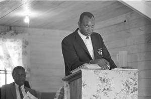 Ralph Featherstone speaking to an audience in a small wooden church building in Lowndes County, Alabama.