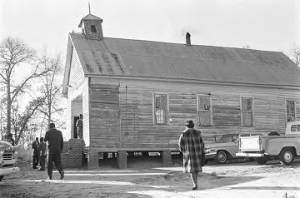 People entering a wooden church building in rural Prattville, Alabama, probably for a meeting of the Autauga County Voters Association.
