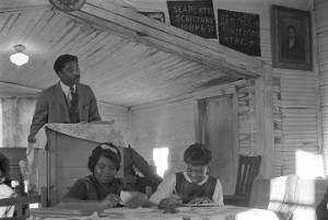 Norman Lumpkin speaking to an audience in a small wooden church building in Prattville, Alabama, probably during a meeting of the Autauga County Voters Association.